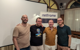 Foto di gruppo con il relatore al meetup Modena Full Stack sul monitoraggio cloud, davanti al roll-up Netframe