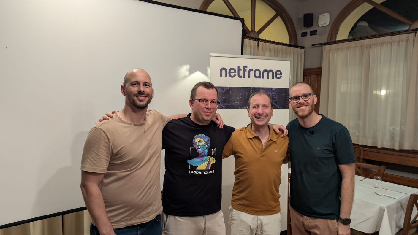 Foto di gruppo con il relatore al meetup Modena Full Stack sul monitoraggio cloud, davanti al roll-up Netframe